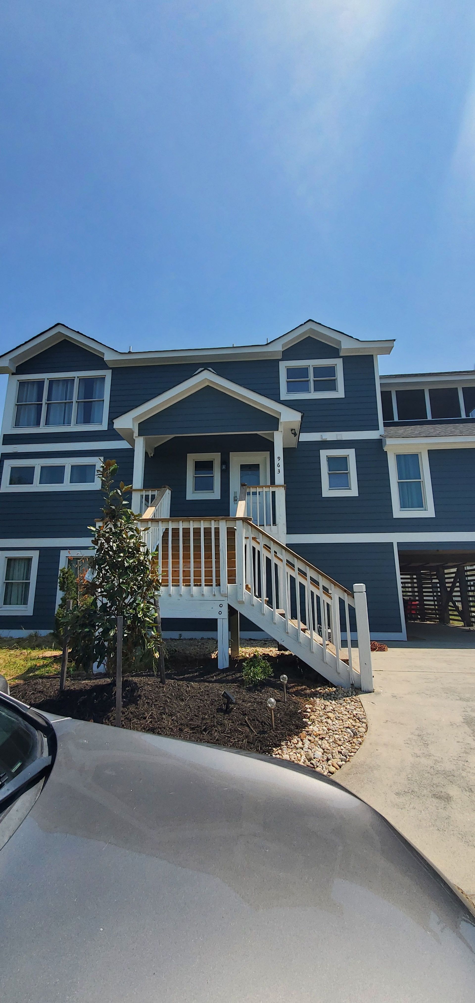 Blue apartment building with white trim and a front staircase under a clear sky