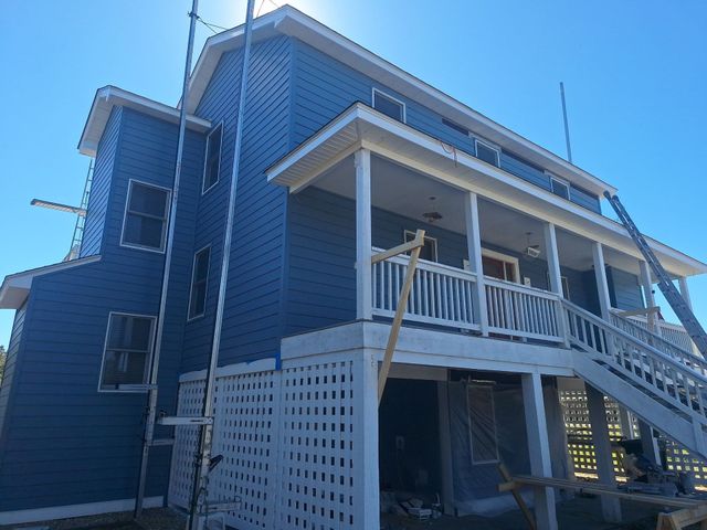 Blue two-story house with white balcony and stairs viewed from below