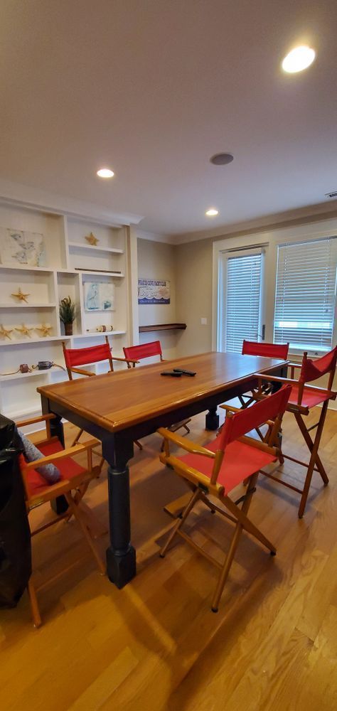 Dining room with wooden table, red chairs, white shelving, and a window with blinds