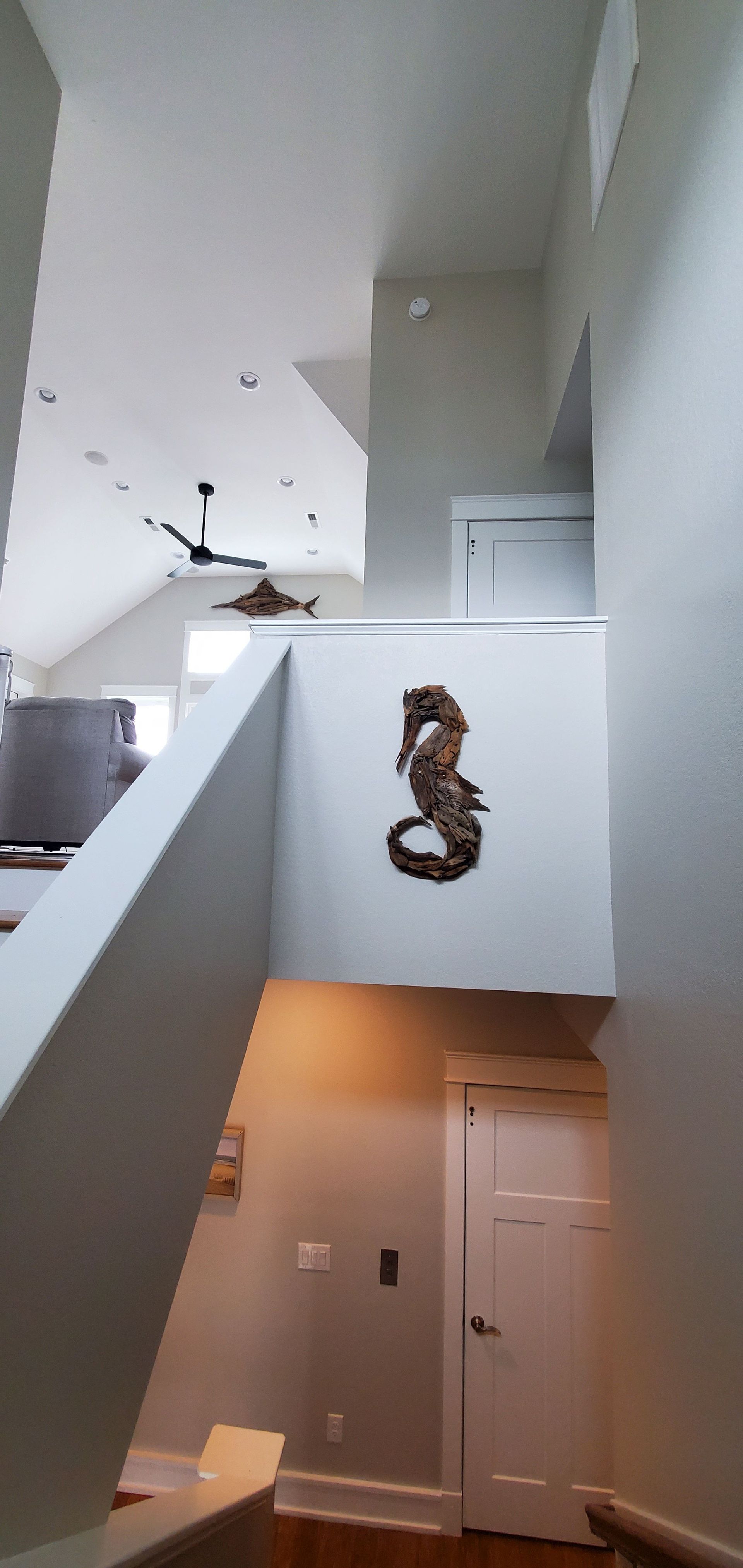 Interior stairwell with white walls, ceiling fan, and a decorative wreath hanging above a door.