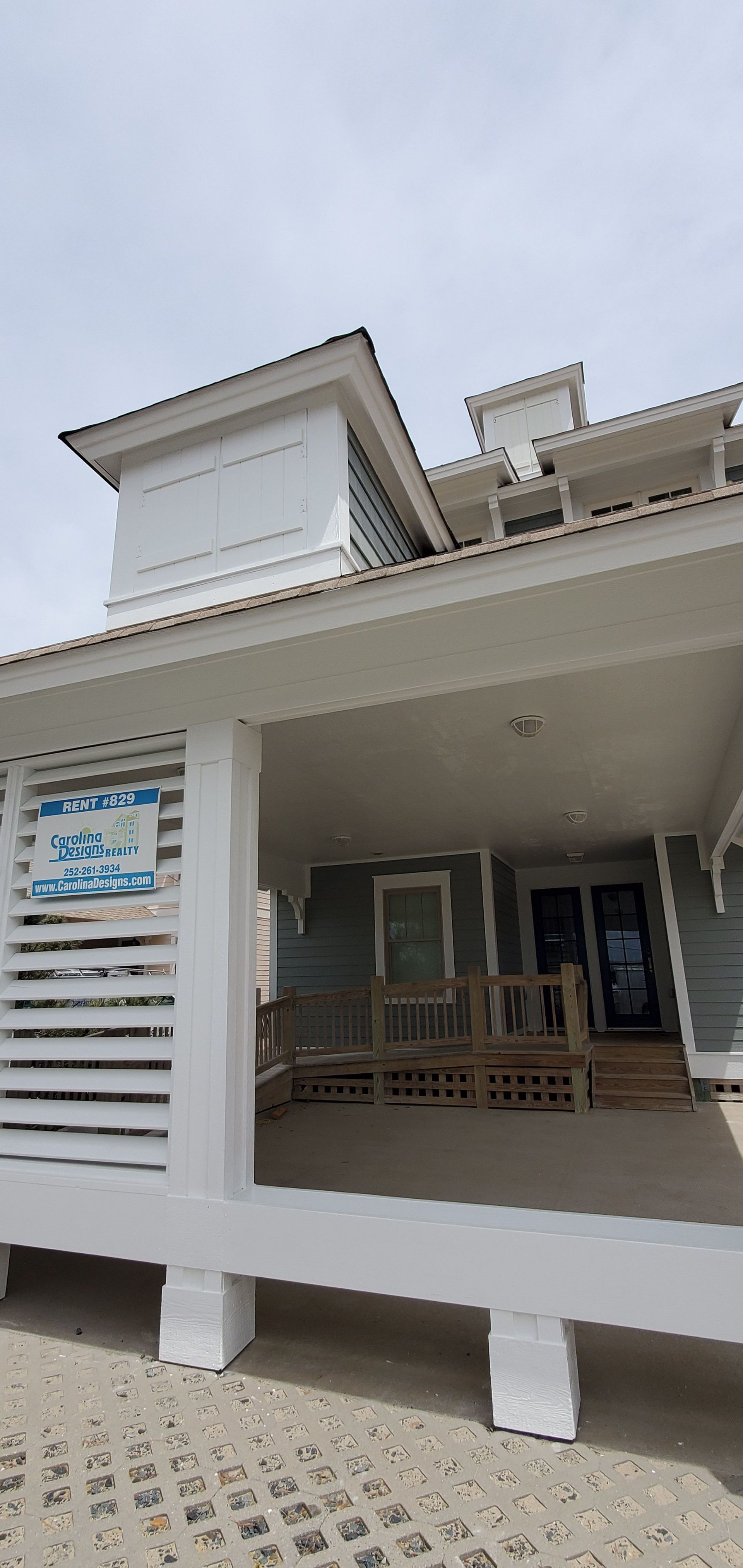 White two-story porch with a covered entrance, railings, steps, and blue signboards on the front facade