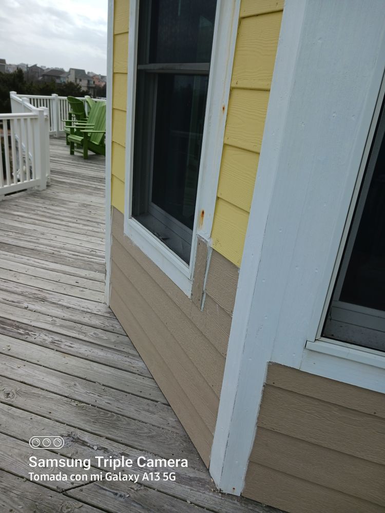 Weathered wooden deck beside a yellow house with white trim and sliding glass doors