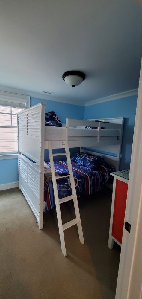 Bedroom with a white bunk bed, blue walls, and an open closet beside a window.