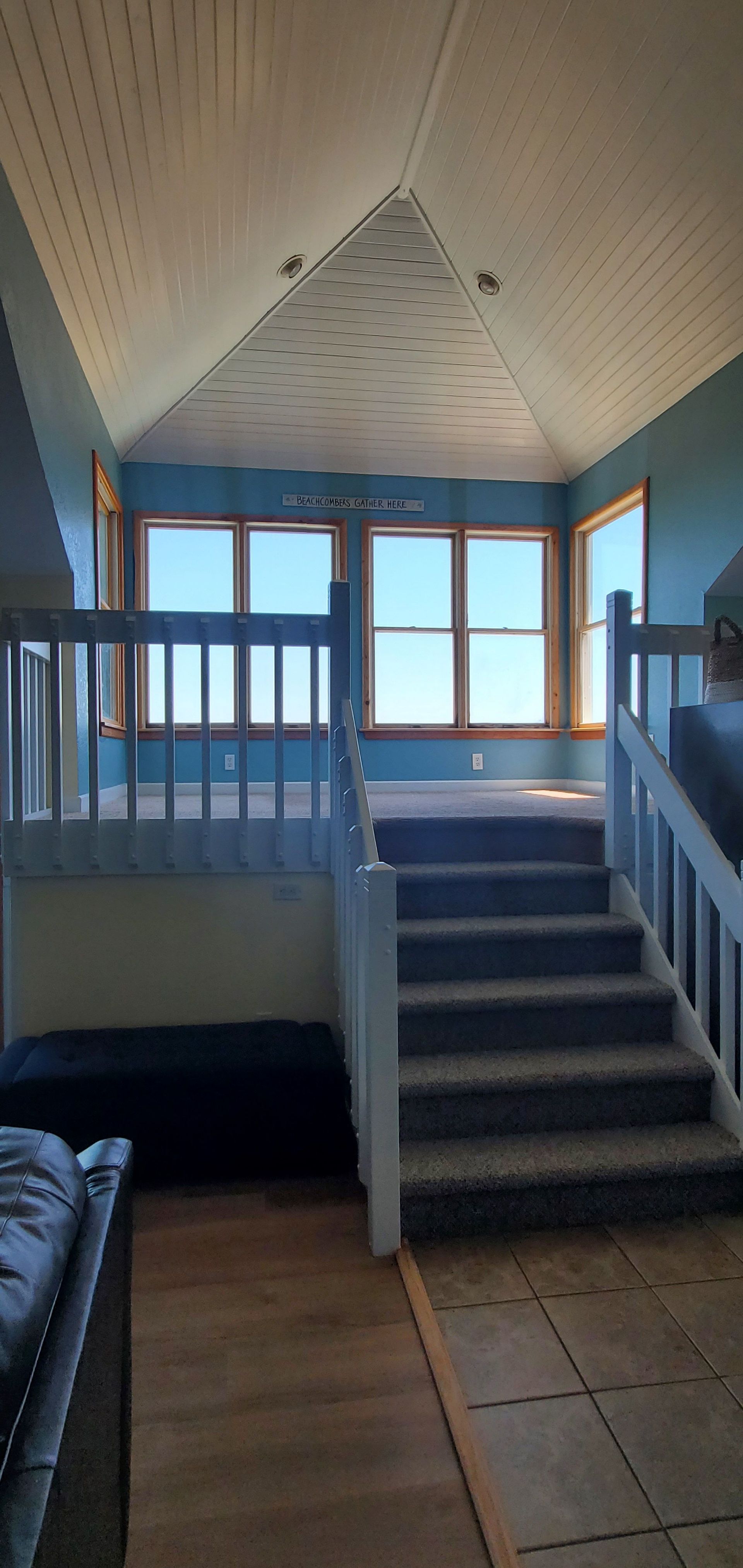 Staircase leading to a bright blue-railed landing with windows and tiled floor in a home interior