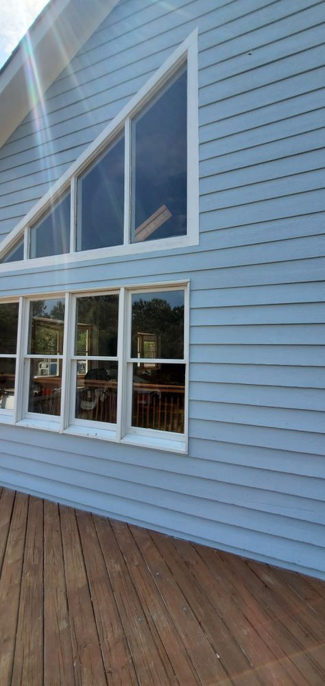 Blue house exterior with large triangular windows and a wooden deck