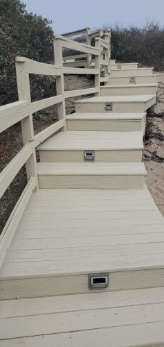 Steep beige outdoor staircase with white railings on a rocky hillside