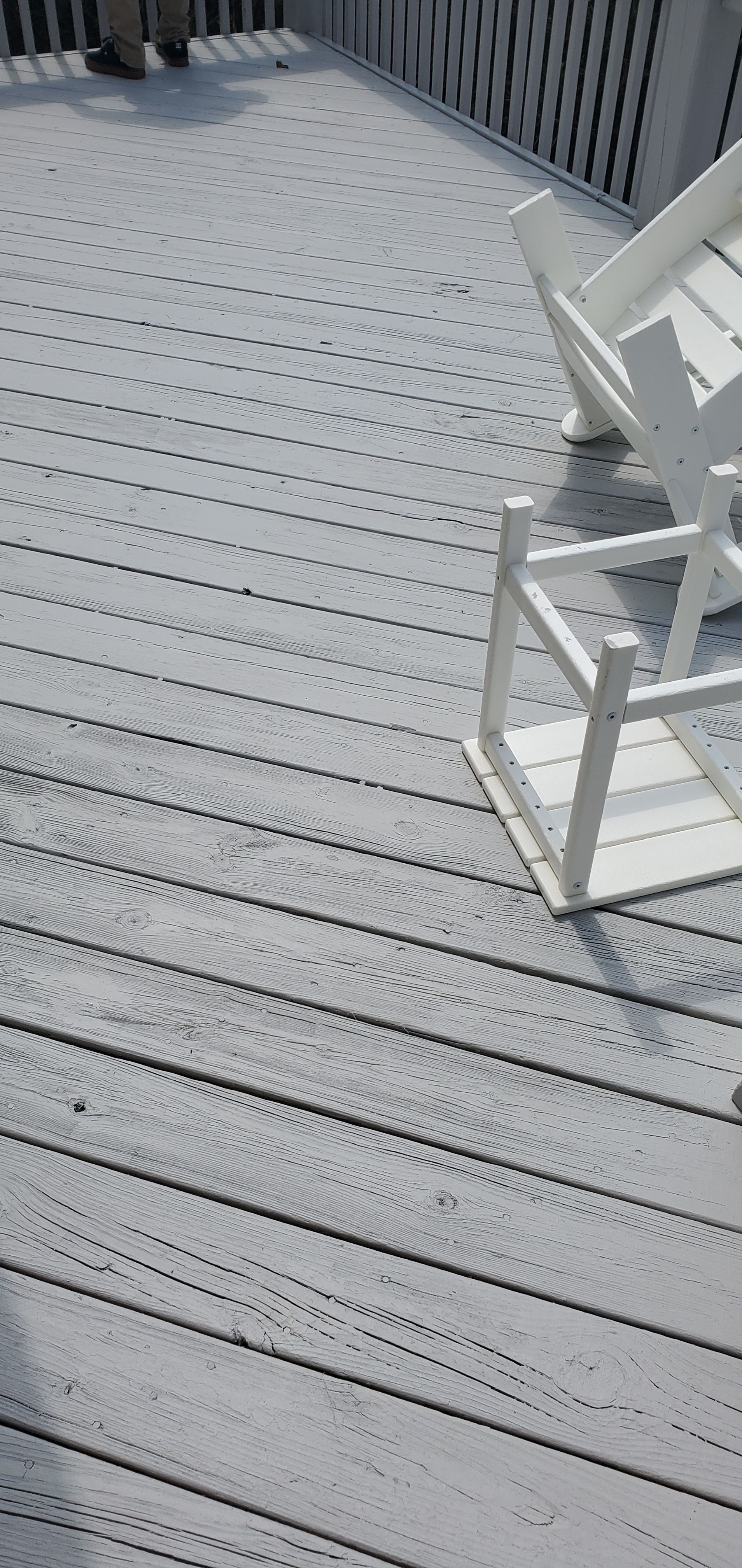 Gray deck with railings and a white chair, viewed from above