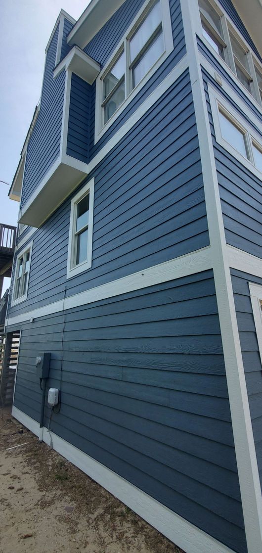 Blue two-story building with white trim and clapboard siding, viewed from a low angle outdoors.