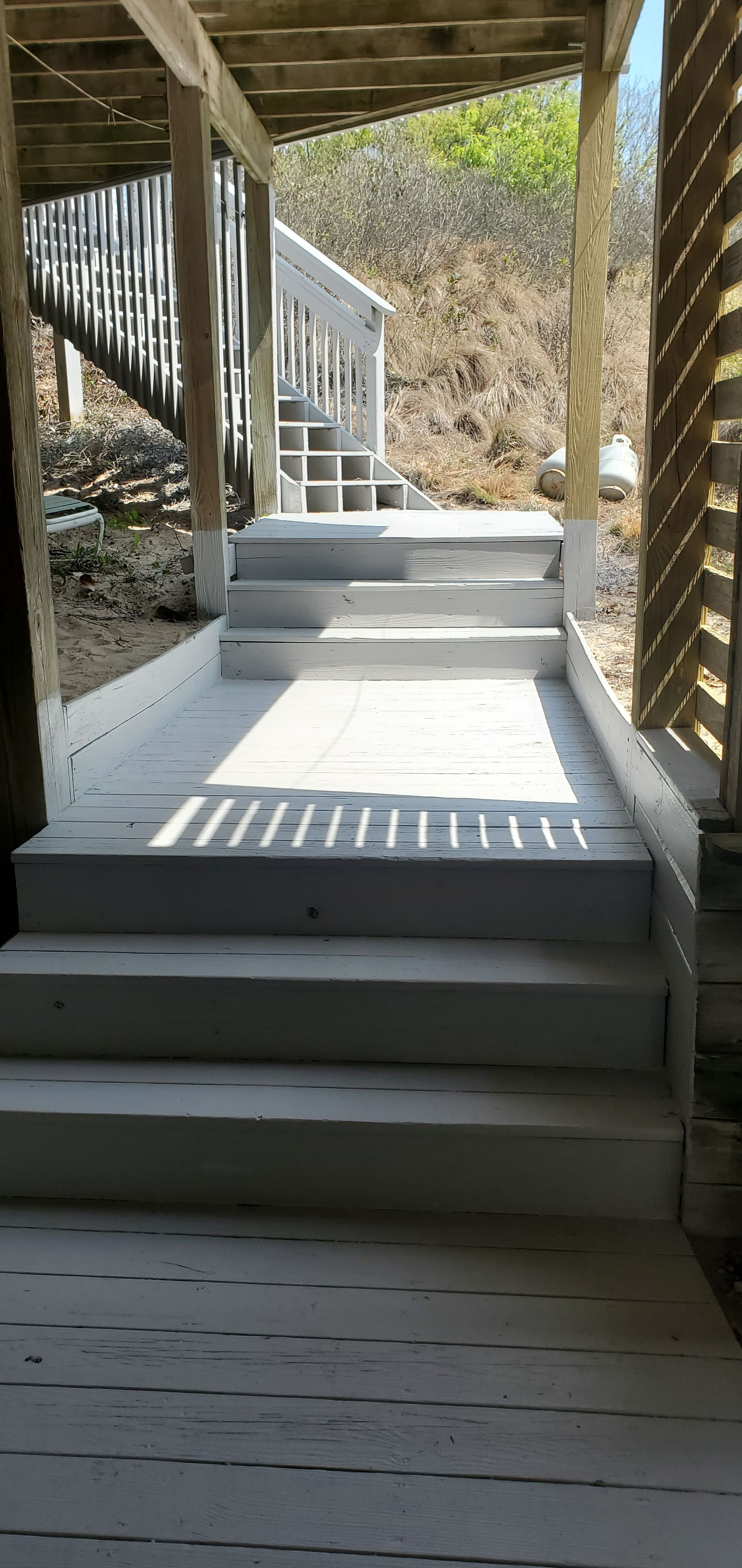 Covered outdoor stairs with white steps and railings beside a hillside path