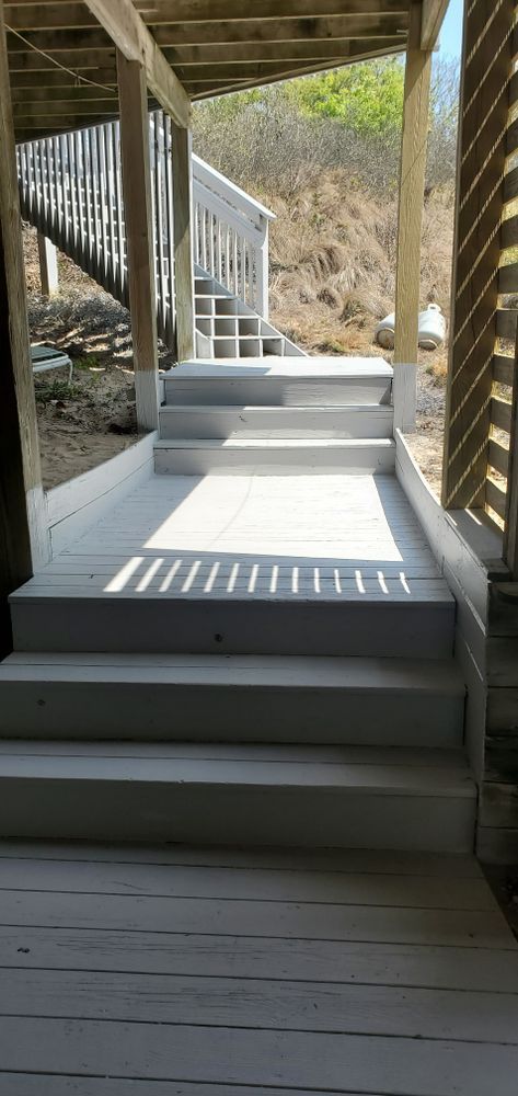 Covered wooden stairway leading down a hillside path with railings and bright sunlight.