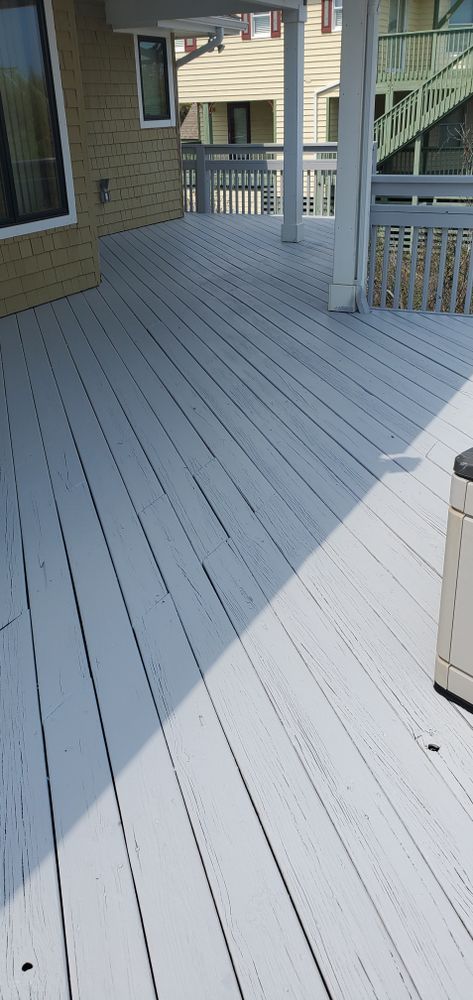 White painted wooden deck beside a house, with railing and steps leading to a porch.