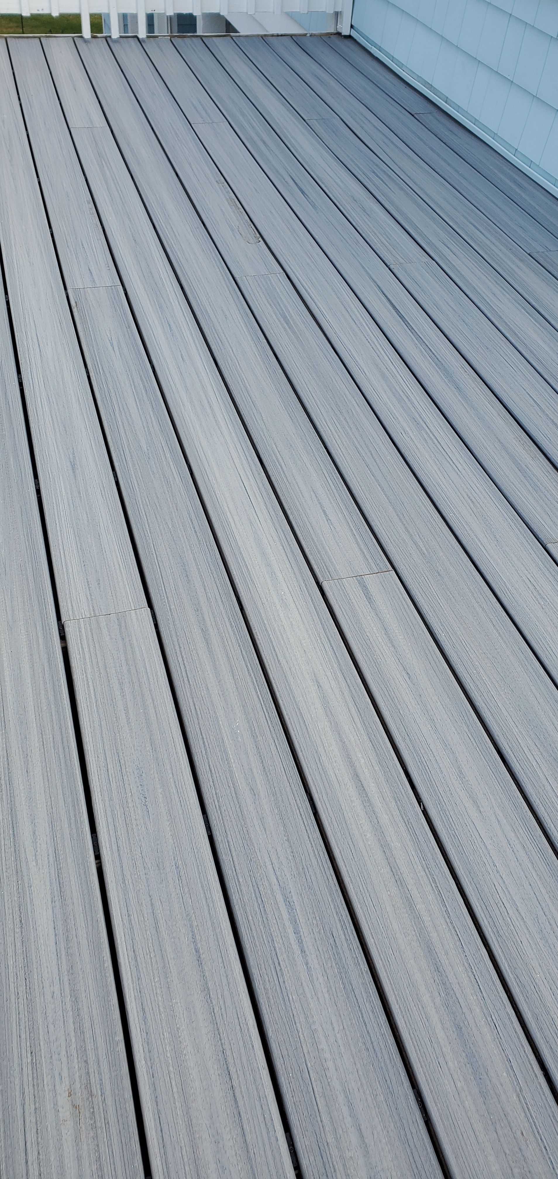 Gray ribbed metal rooftop or deck surface with diagonal lines and a white wall at the top.