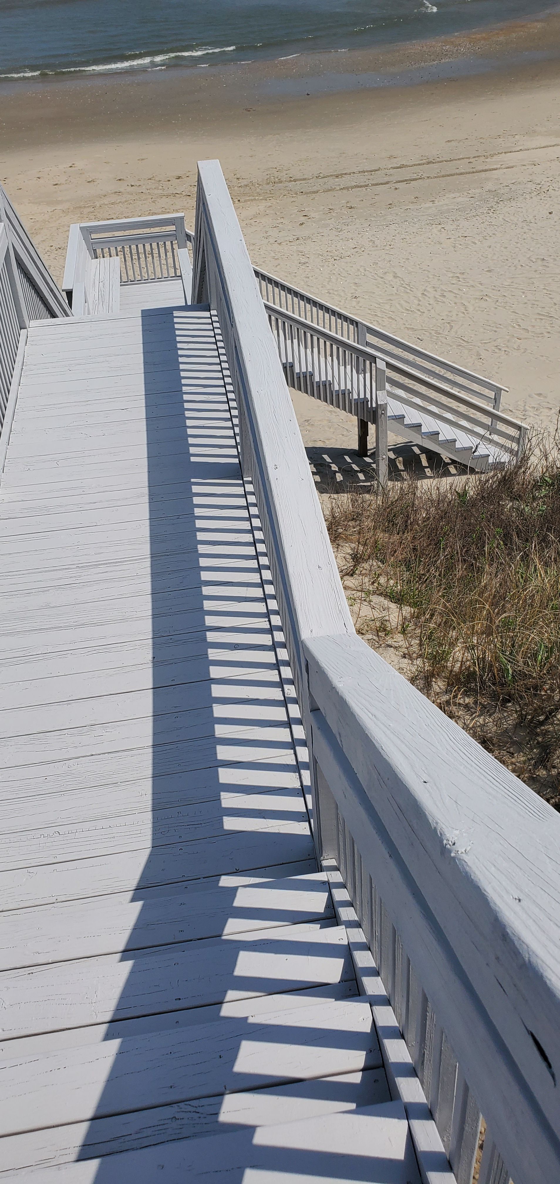 Wooden boardwalk stairs descending to a sandy beach beside the ocean