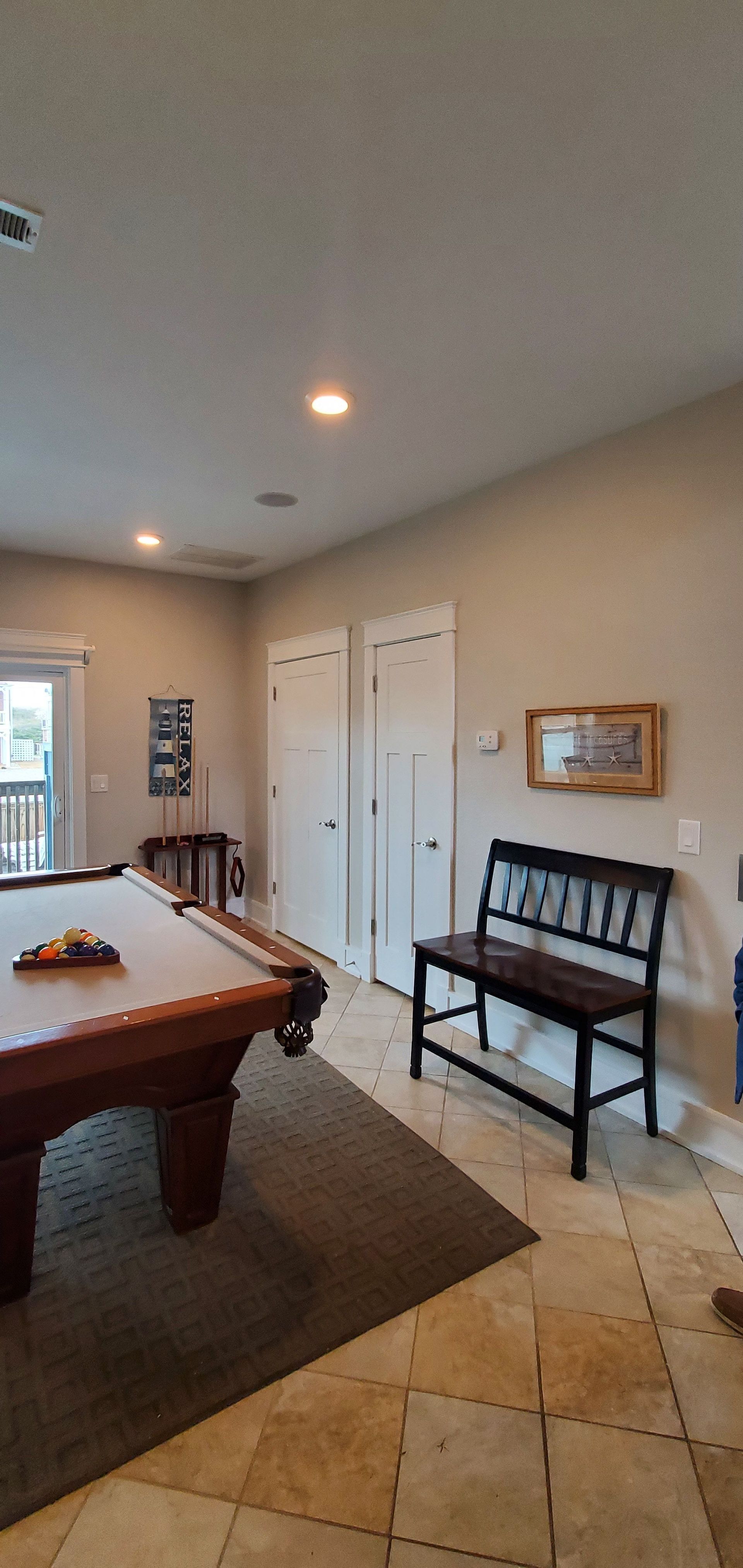 Spacious game room with a pool table, bench, tiled floor, and white double doors under recessed lights