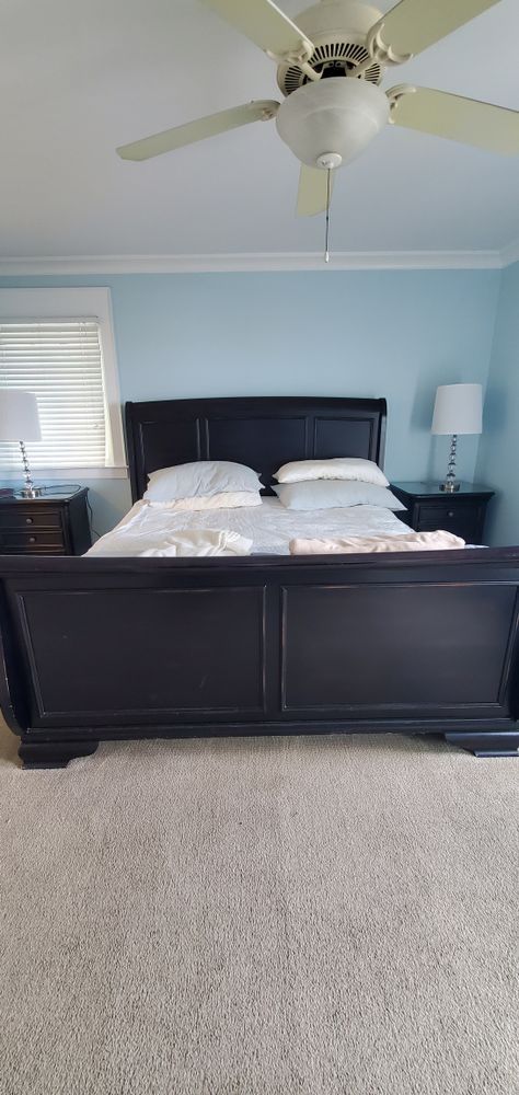 Bedroom with dark wood bed, white bedding, ceiling fan, and gray carpet