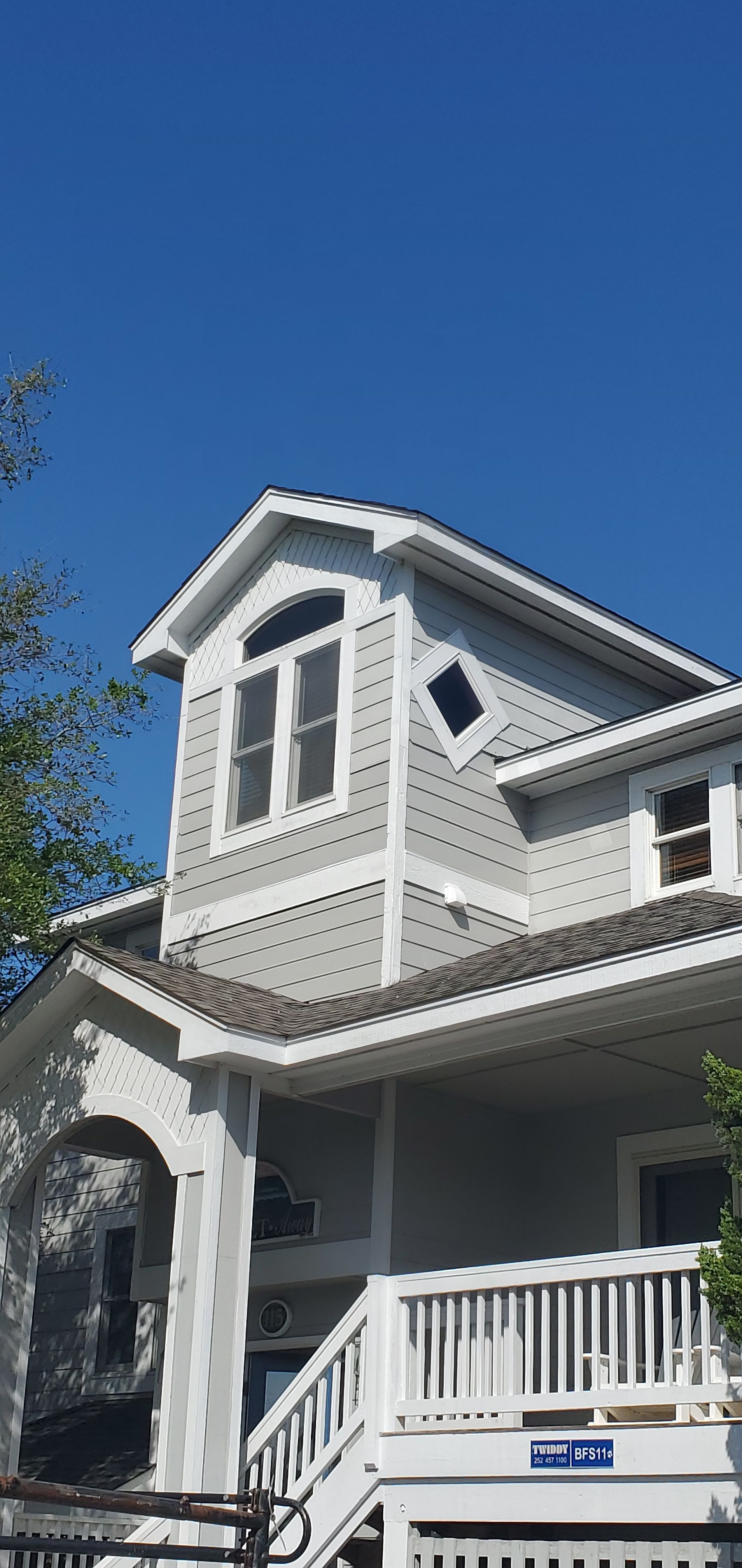 Gray house with white trim and porch under a clear blue sky