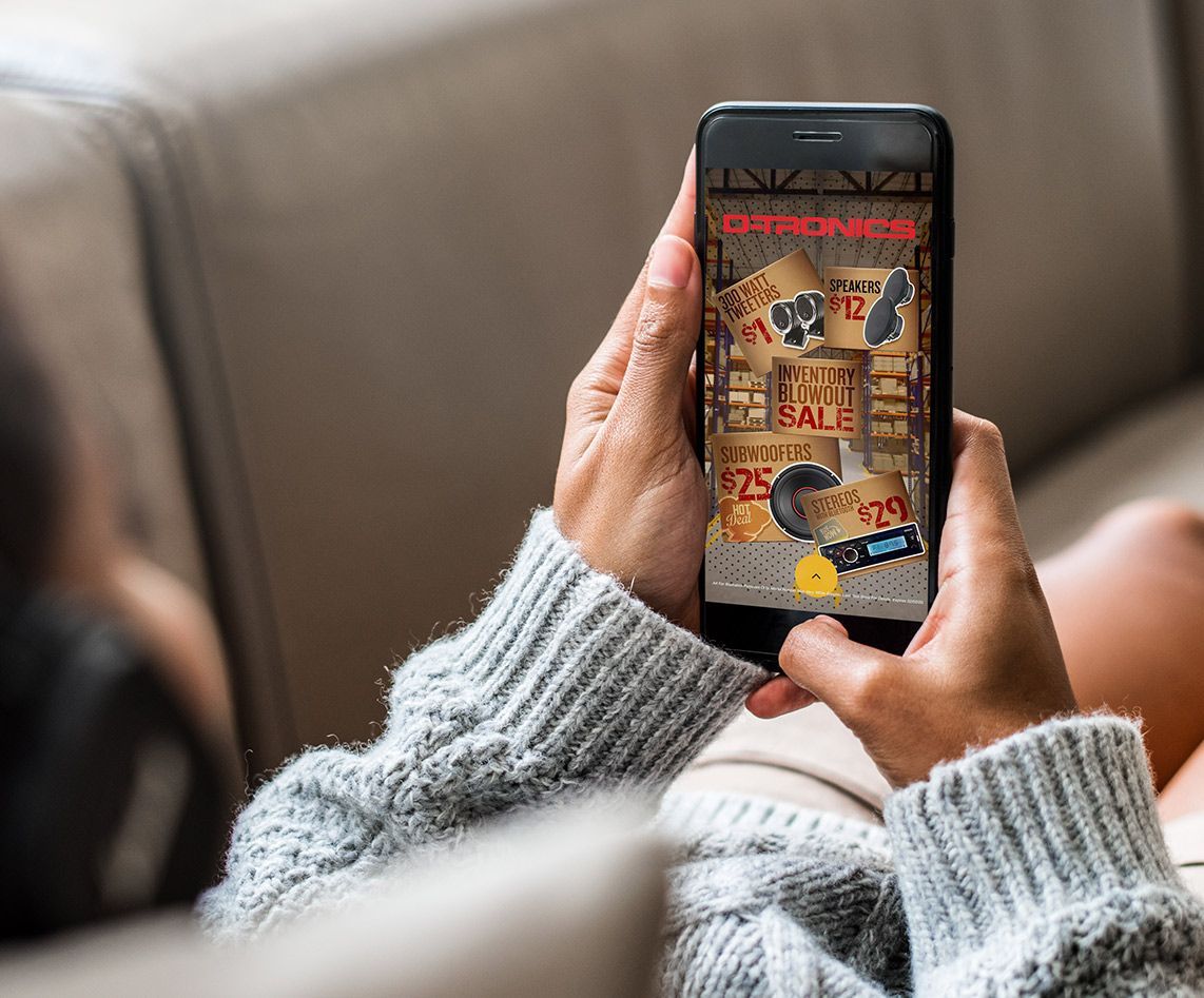 A person is sitting on a couch holding a cell phone in their hands.