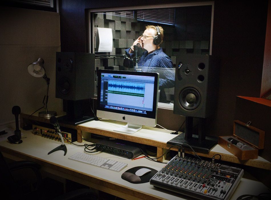 A man is singing into a microphone in a recording studio.