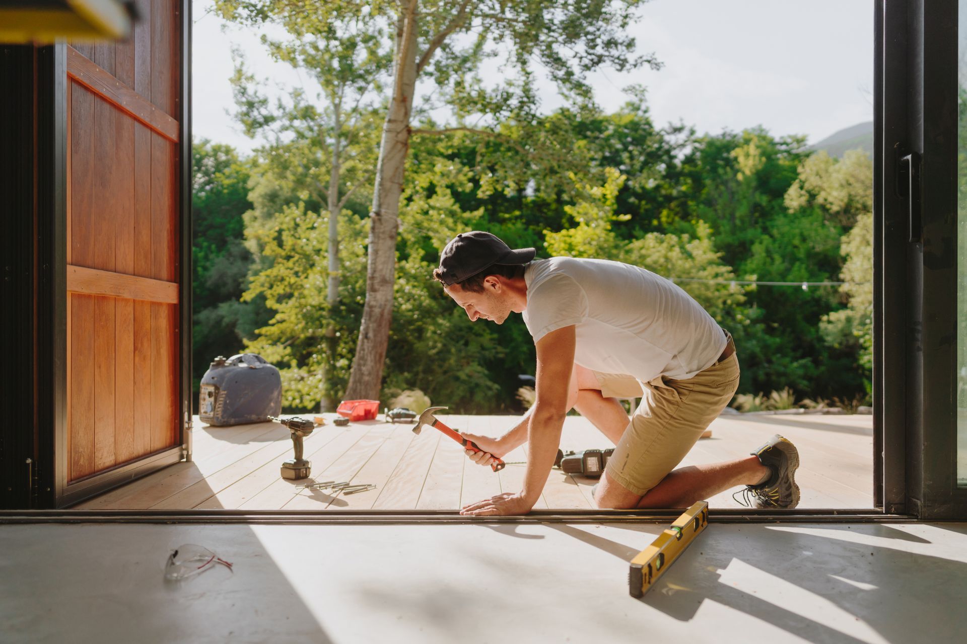 Man building wooden deck outside cabin using tools and materials from a trusted deck supply source.