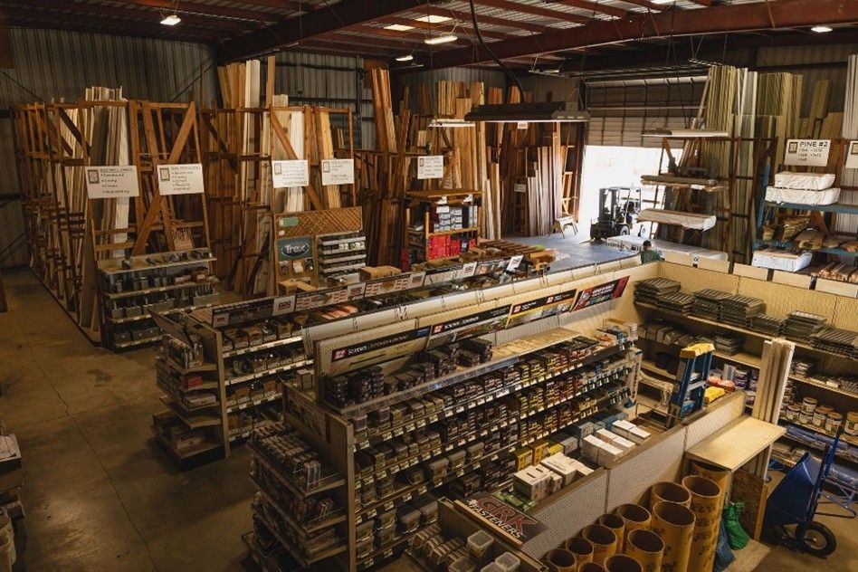 A lumber yard warehouse with stacked wood planks, hardware aisles, and construction supplies A lumber yard warehouse with stacked wood planks, hardware aisles, and construction supplies