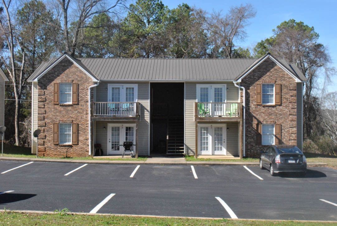 A brick apartment building with a car parked in front of it. Ladiga Hills.