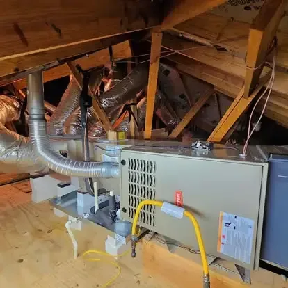Attic HVAC furnace with silver ductwork, yellow gas line, and exposed wooden rafters