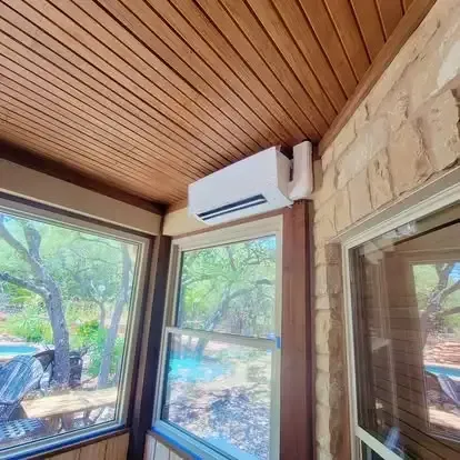 Cozy sunroom with wood ceiling, stone wall, large windows, and a wall-mounted air conditioner