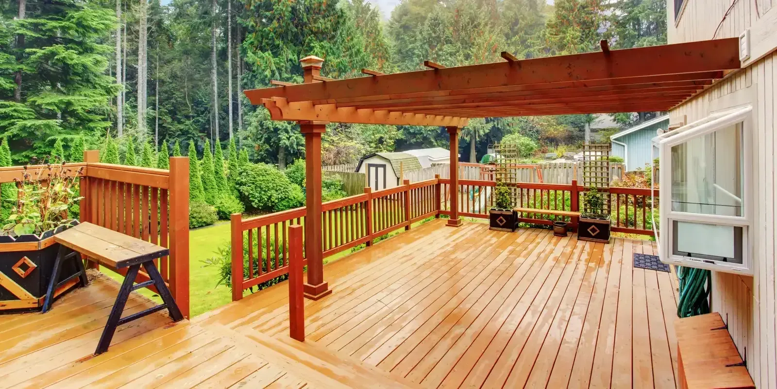Wooden deck with pergola, picnic table, railings, and forest view