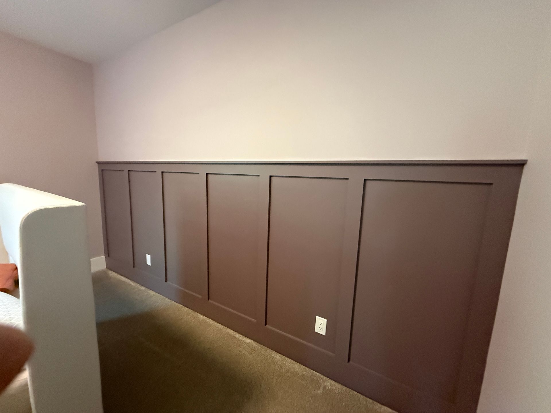 Empty room with dark brown wall panels and a small white cabinet at the left edge