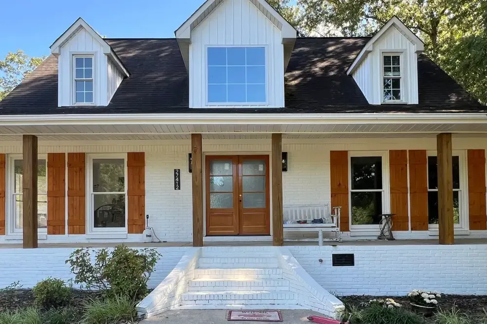 White two-story house with porch, dormer windows, and a centered front walkway