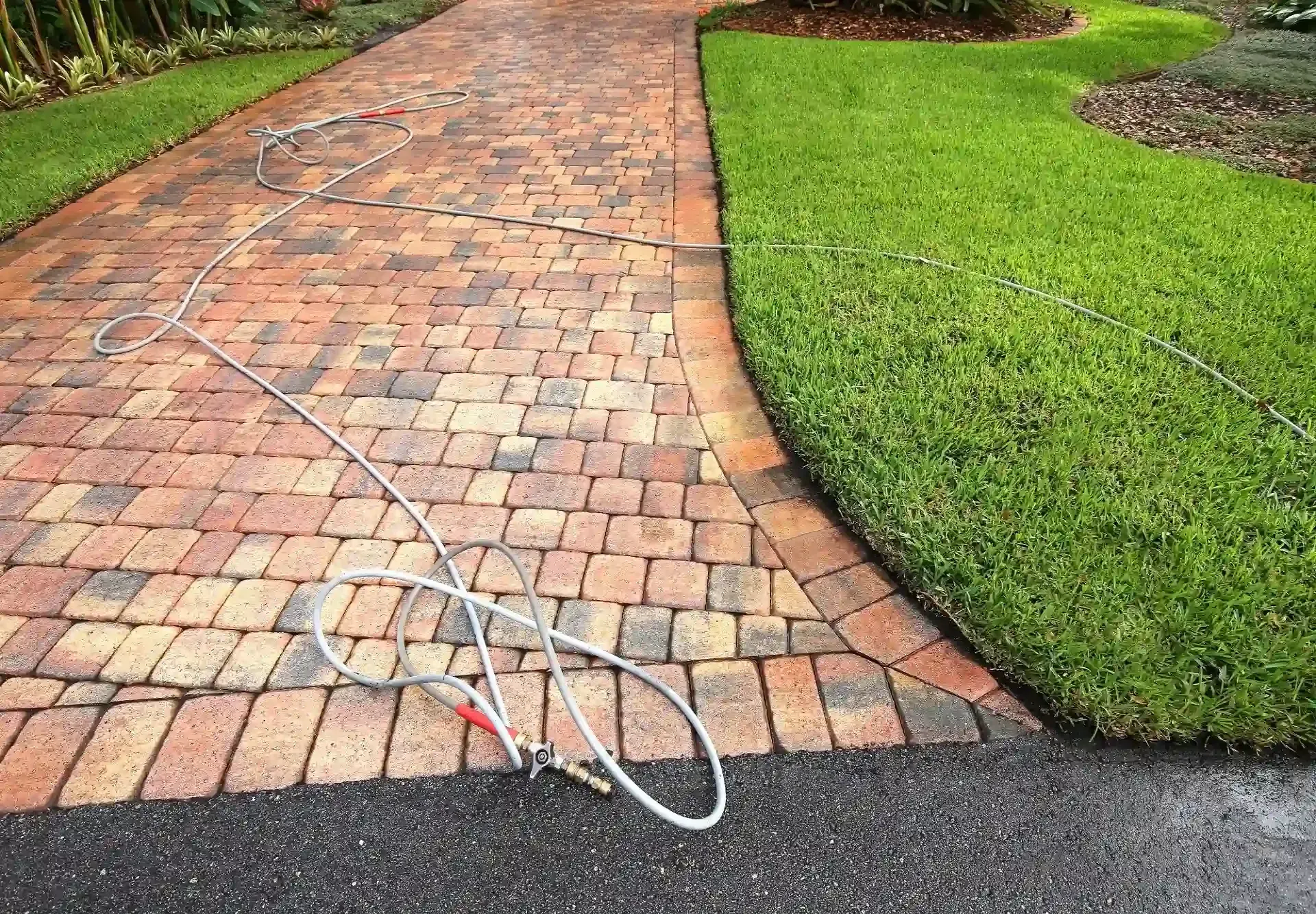 Broken white cable on a brick walkway beside a green lawn.