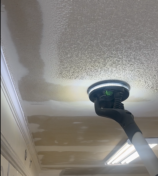 Painted ceiling being sprayed or repaired near a recessed light fixture, with a hose or wand visible.