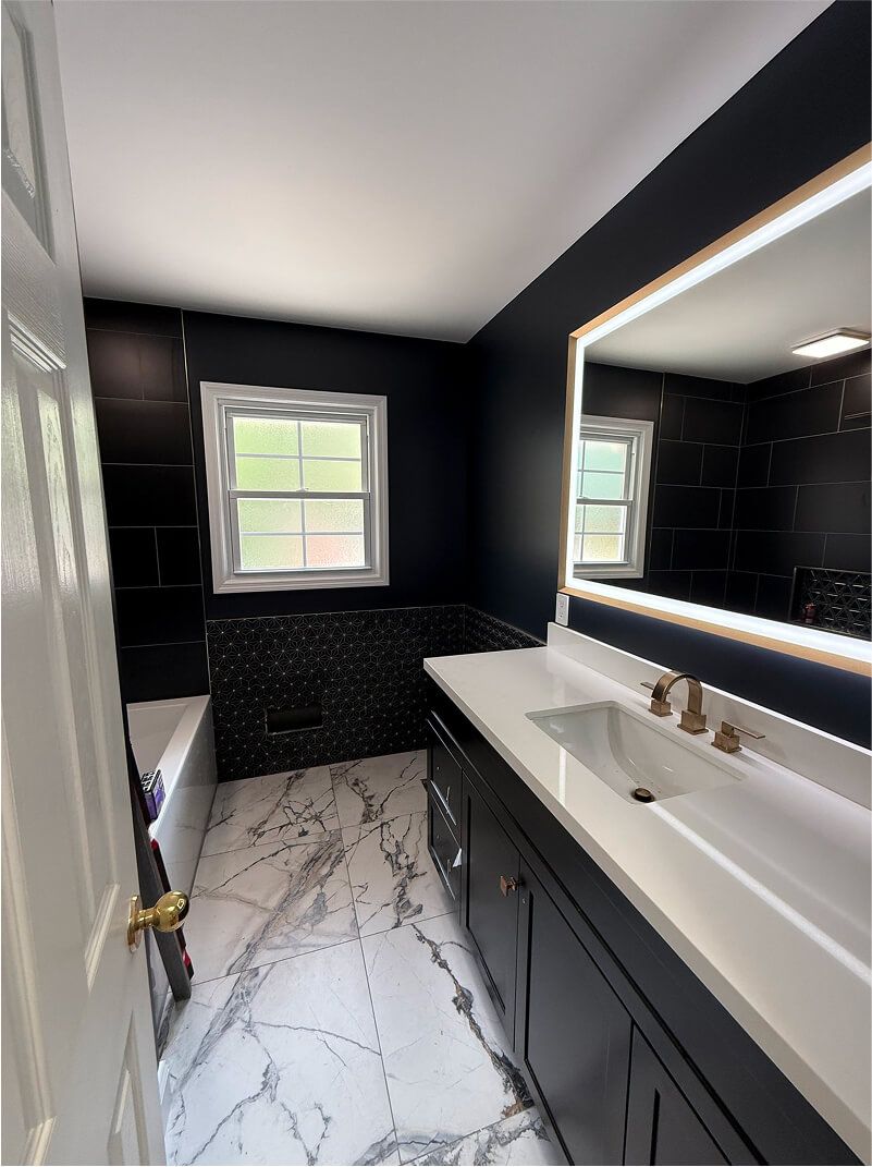 Modern black-and-white bathroom with double sink vanity, large illuminated mirror, and a window.