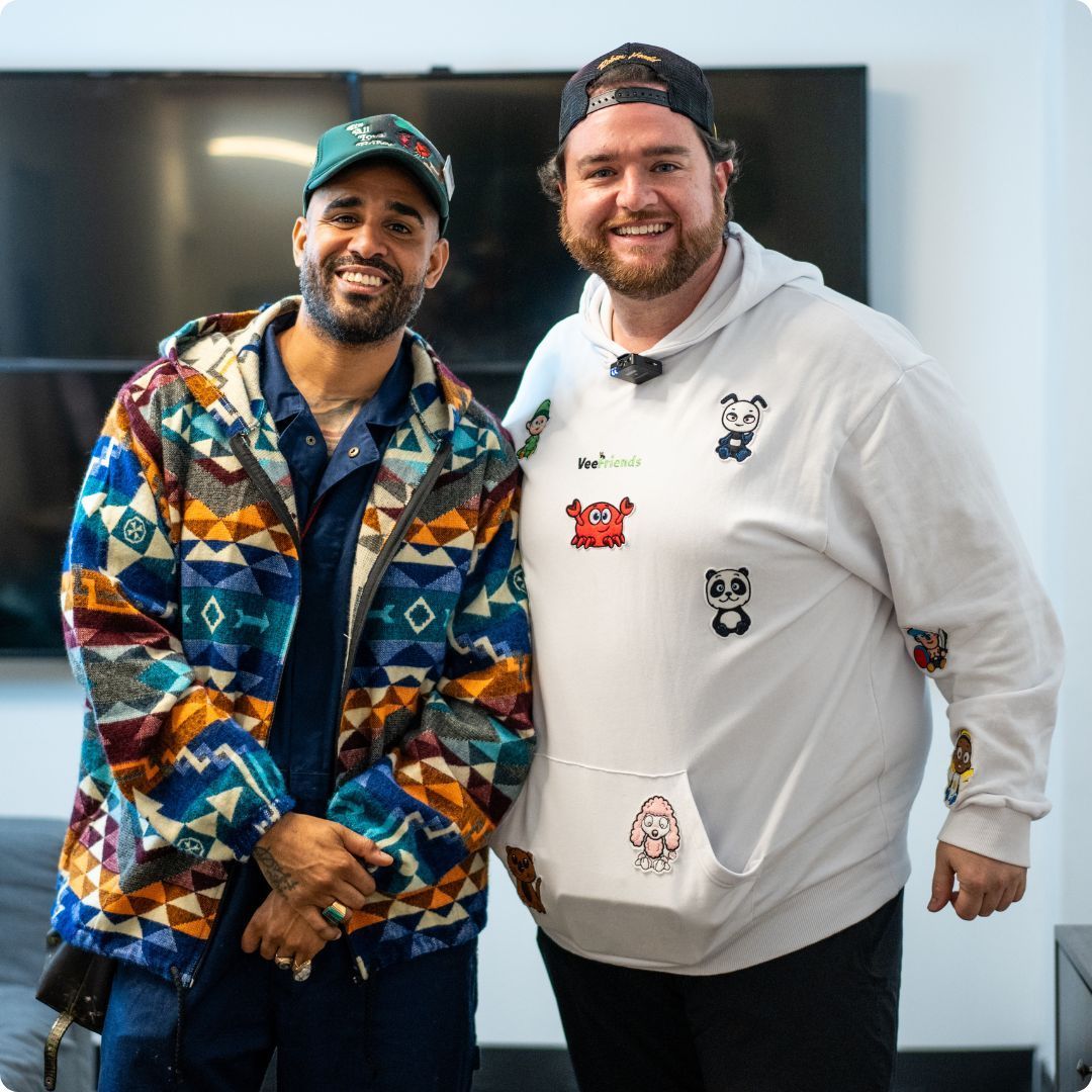 Two men posing for a picture with one wearing a white hoodie