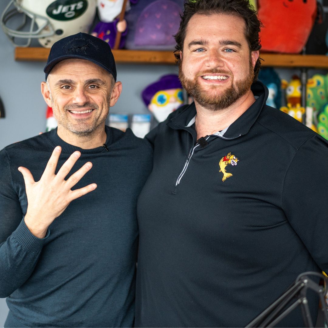 Two men are posing for a picture with a jets helmet in the background