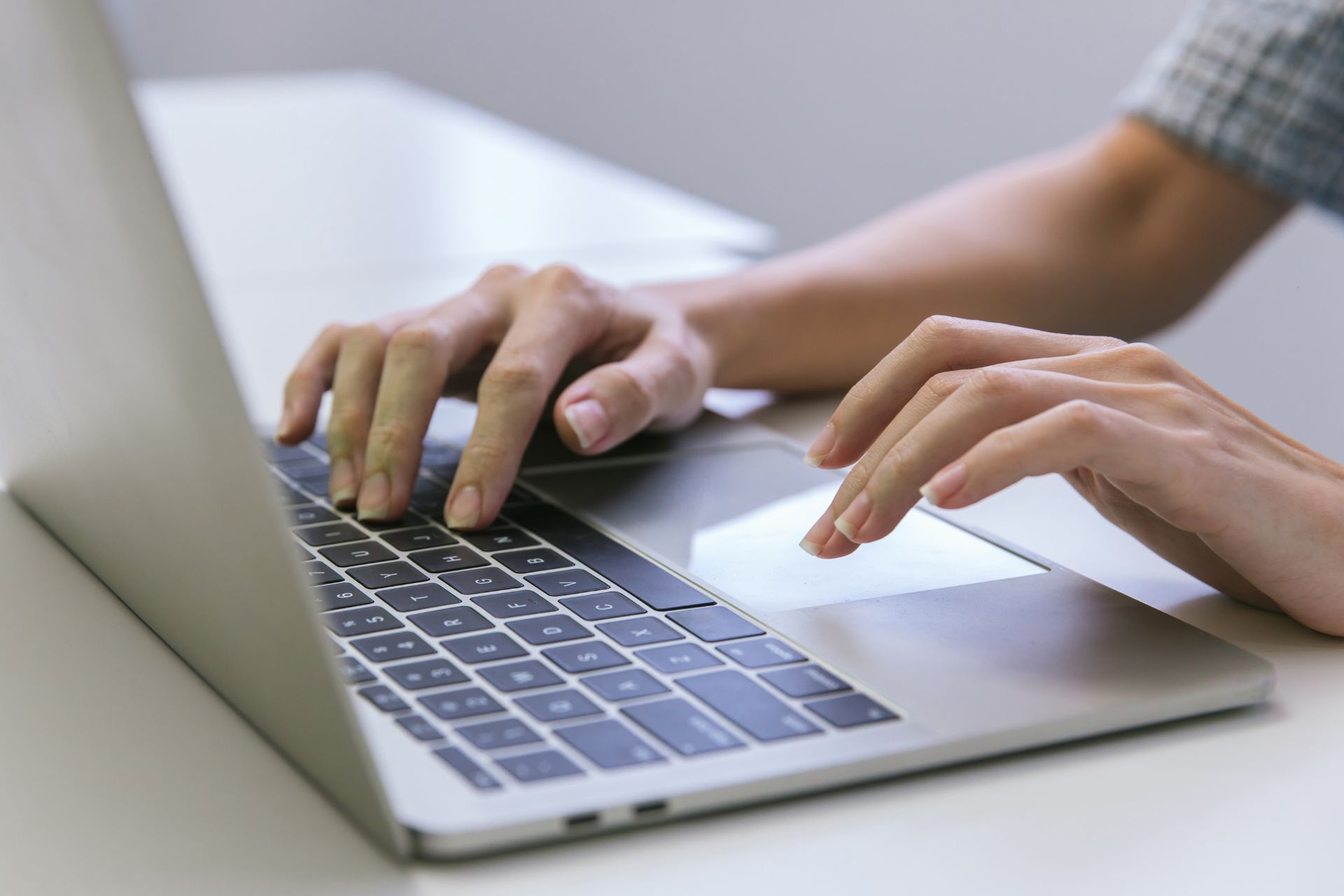 A persons hands on the keyboard of a laptop