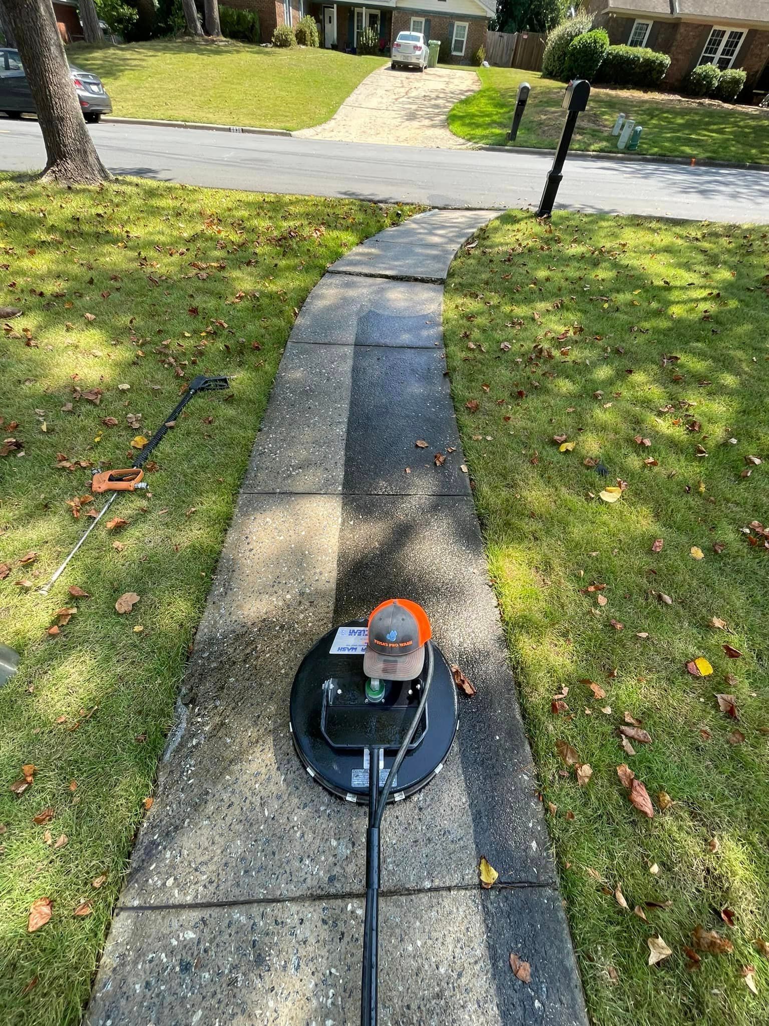 Power washer cleaning a concrete sidewalk in a residential area.