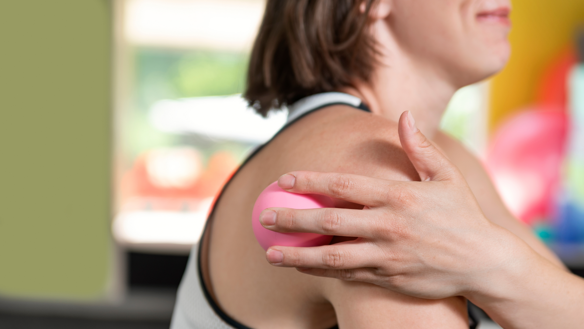 A woman is holding a pink ball on her shoulder.