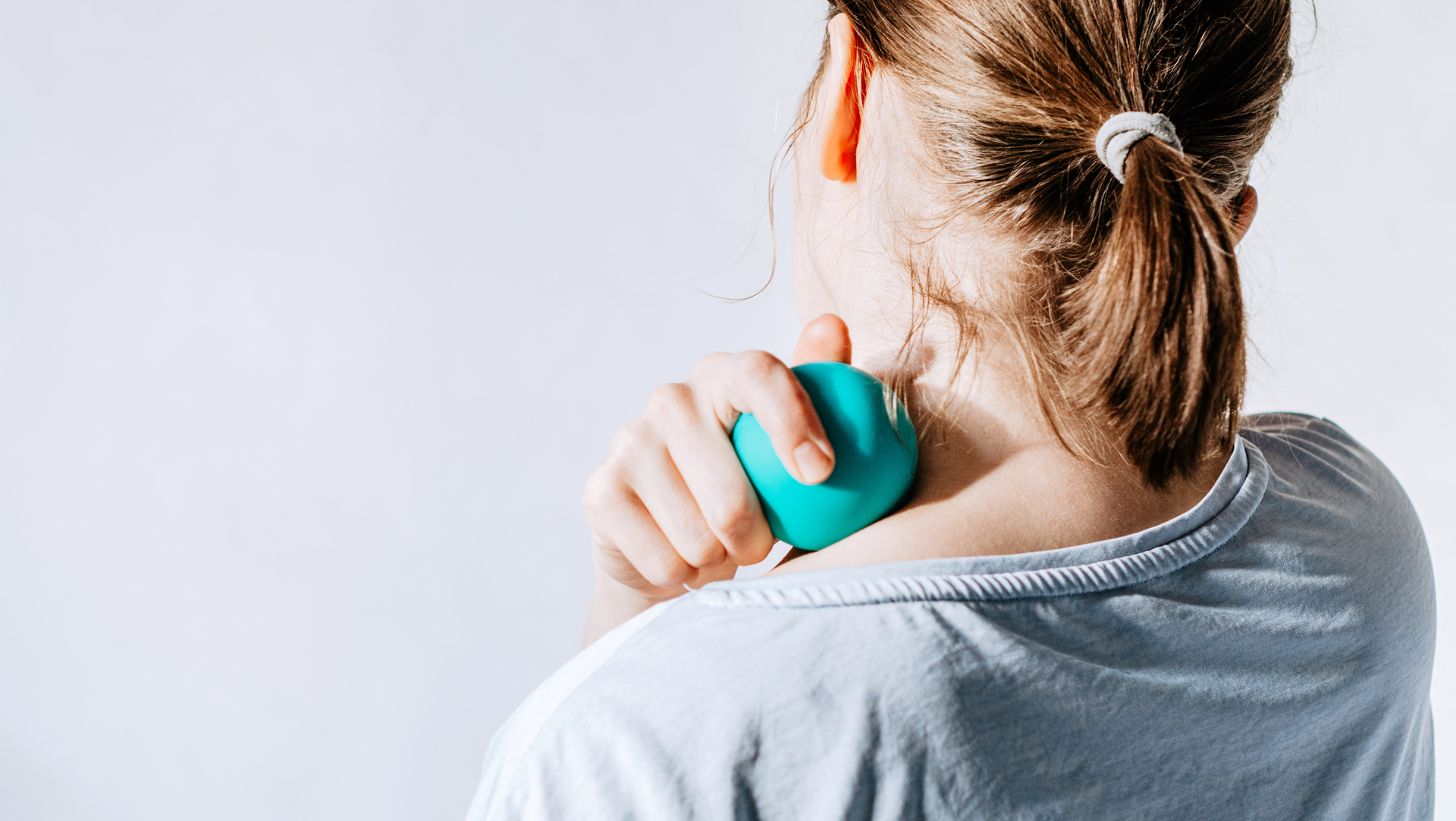 A woman is holding a blue massage ball to her neck.
