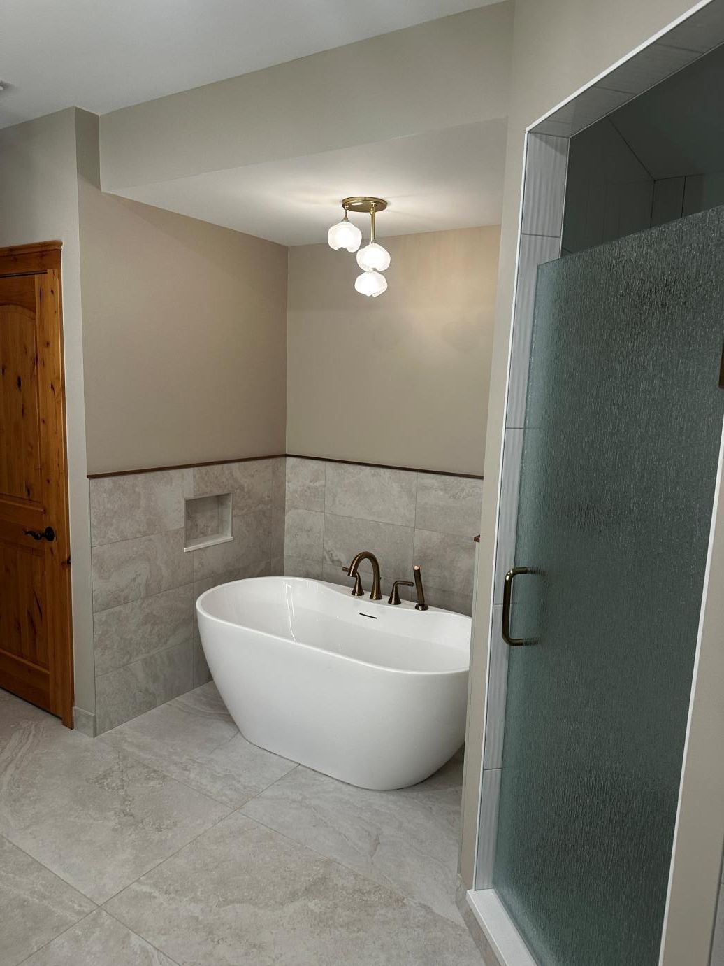 Modern bathroom with freestanding tub, walk-in shower, and light gray tile flooring