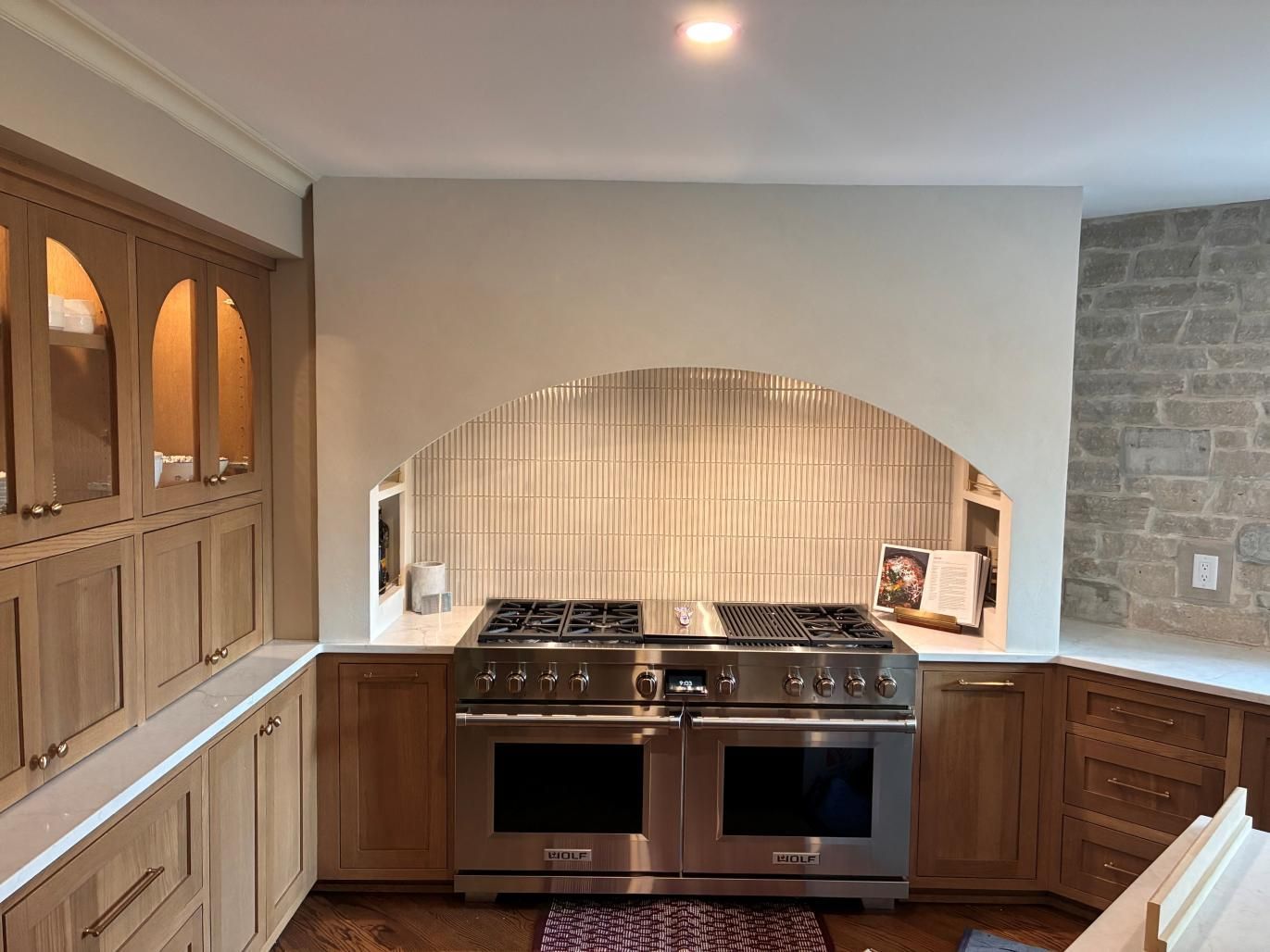 Modern kitchen with built-in cabinets, stainless stove, stone backsplash, and wood flooring
