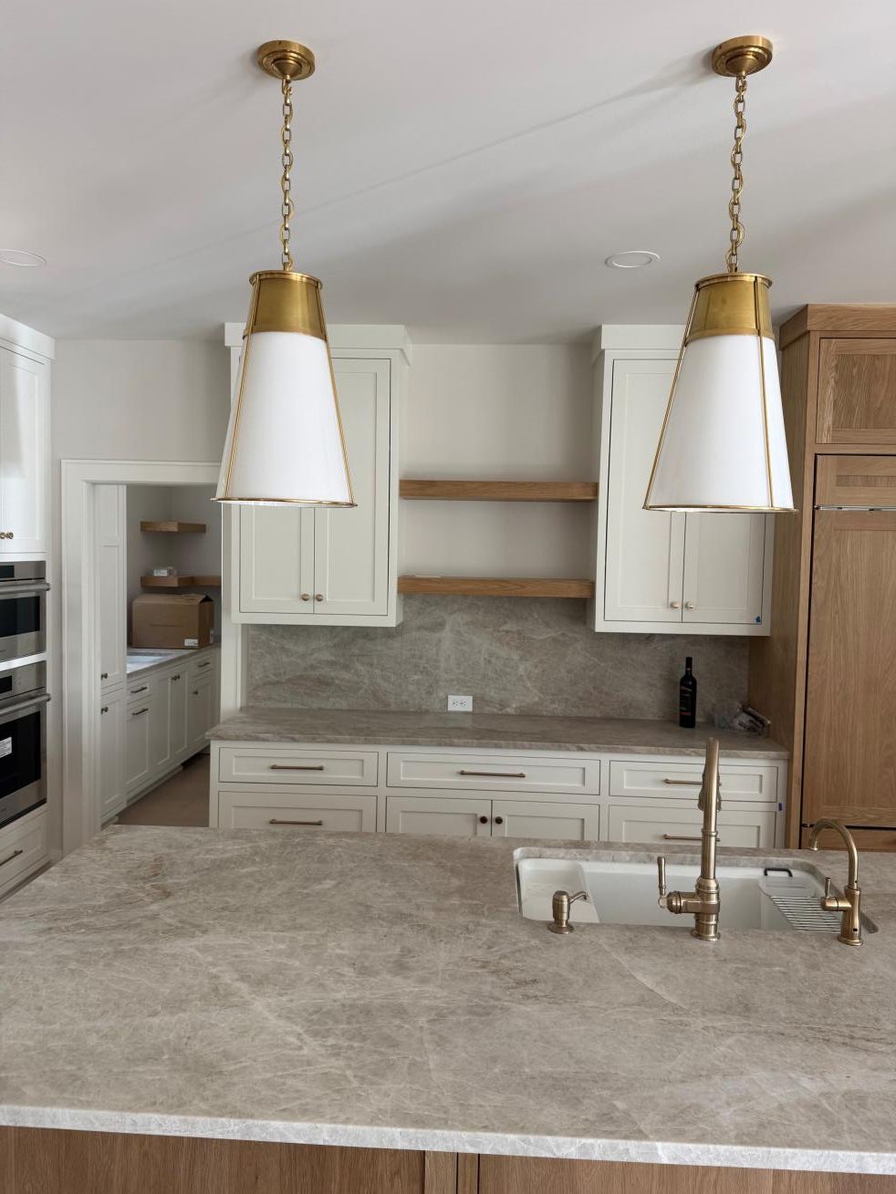 Modern white kitchen with granite island, gold pendant lights, and white cabinetry