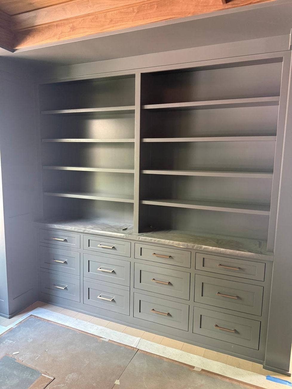 Built-in gray bookshelf with drawers and shelves in a recessed wall alcove