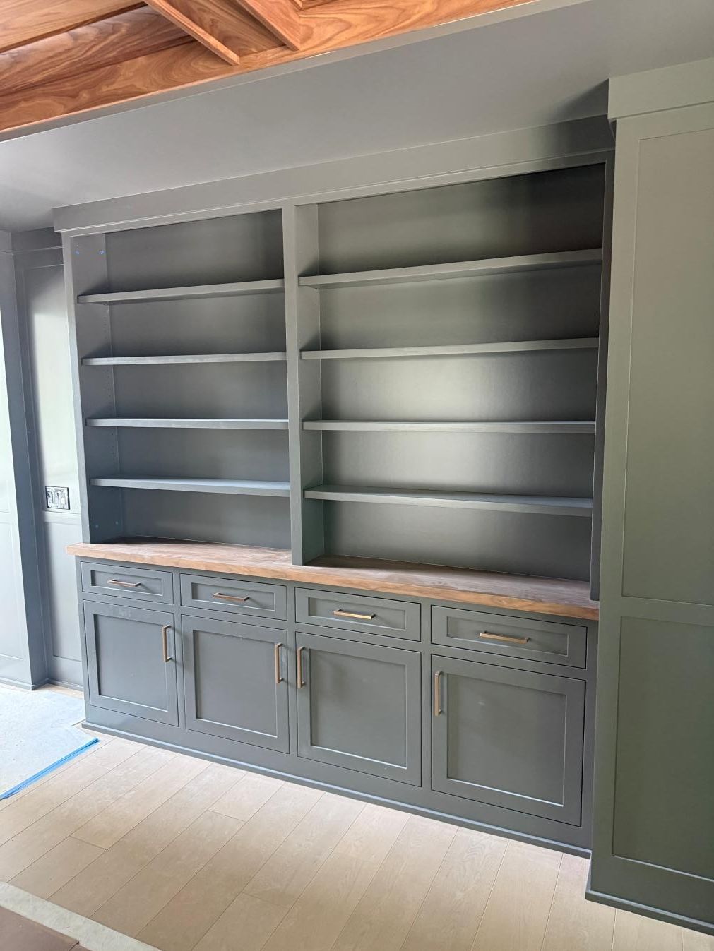 Gray built-in shelving and cabinets against a wall in a bright room.
