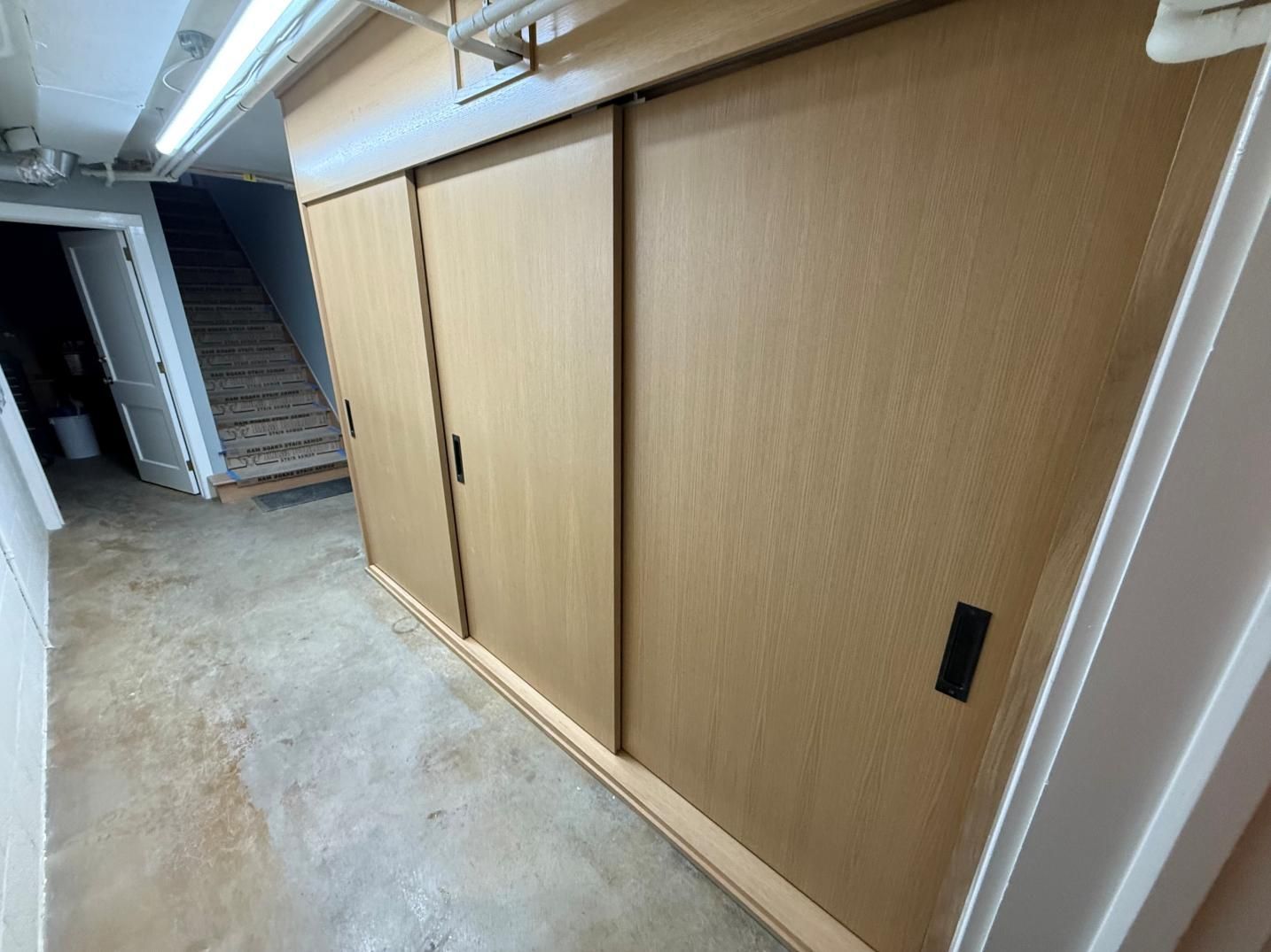 Hallway with large sliding wooden doors and a staircase at the far end