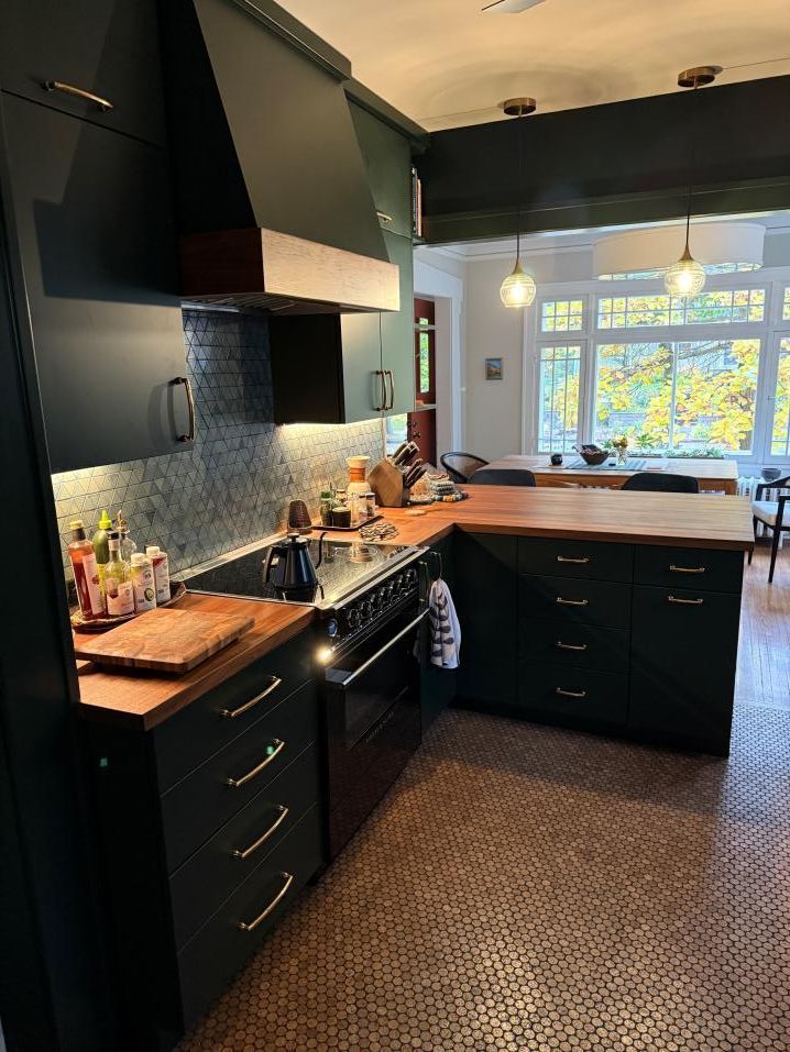 Modern dark kitchen with black cabinets, patterned backsplash, and a bright window over the sink