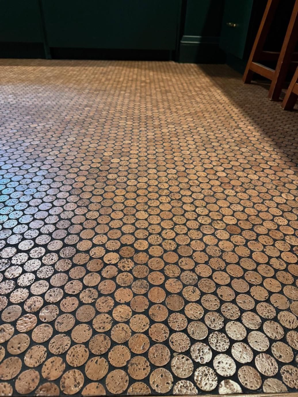 Patterned tile floor in a hallway with green walls and a wooden chair at the right edge