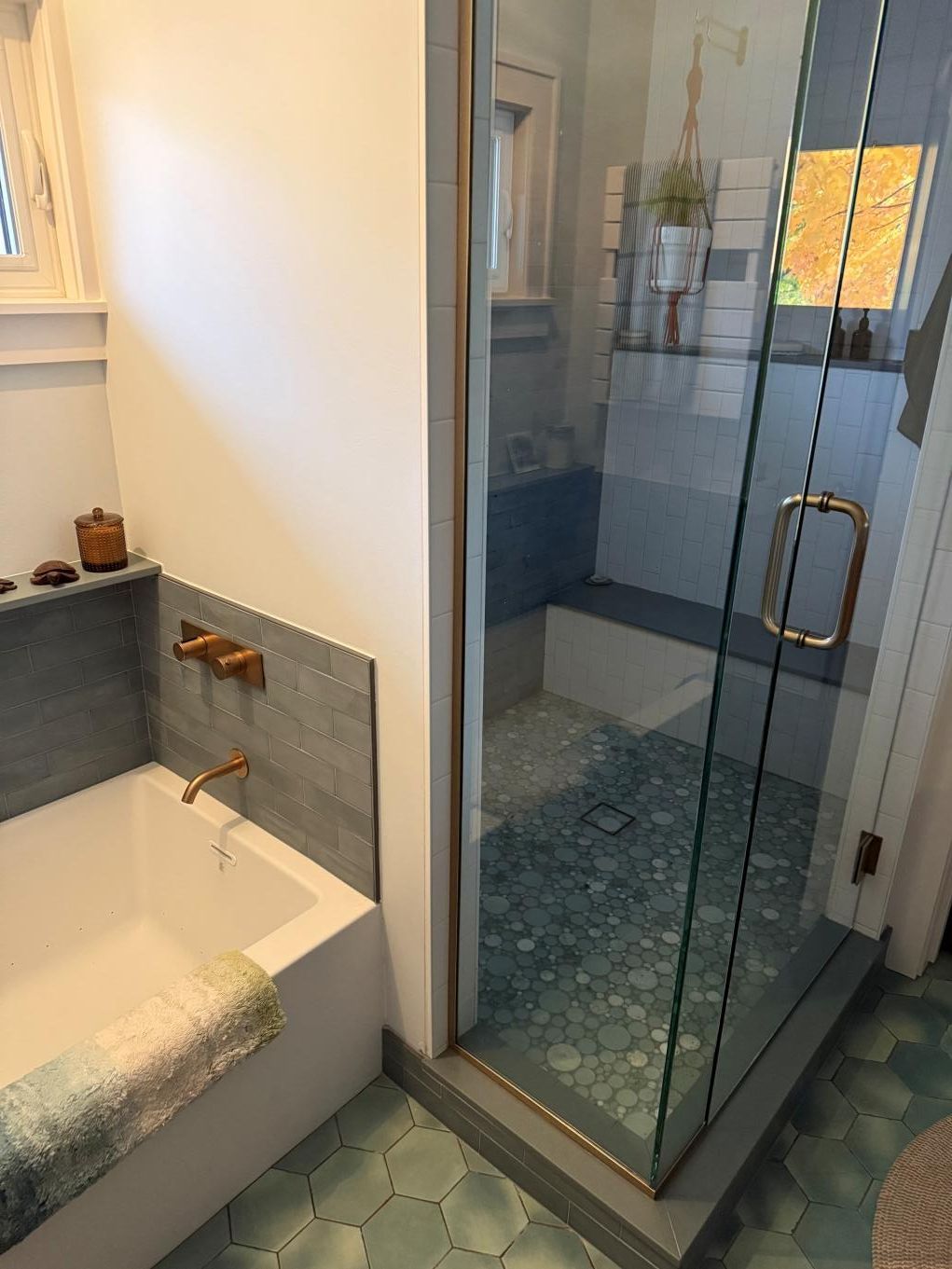 Modern bathroom with freestanding tub, glass shower, and green hex tile floor