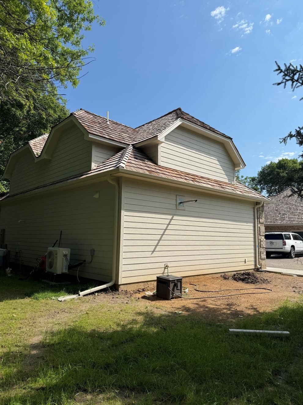 Two-story beige house with tiled roof and white garage in a sunny yard