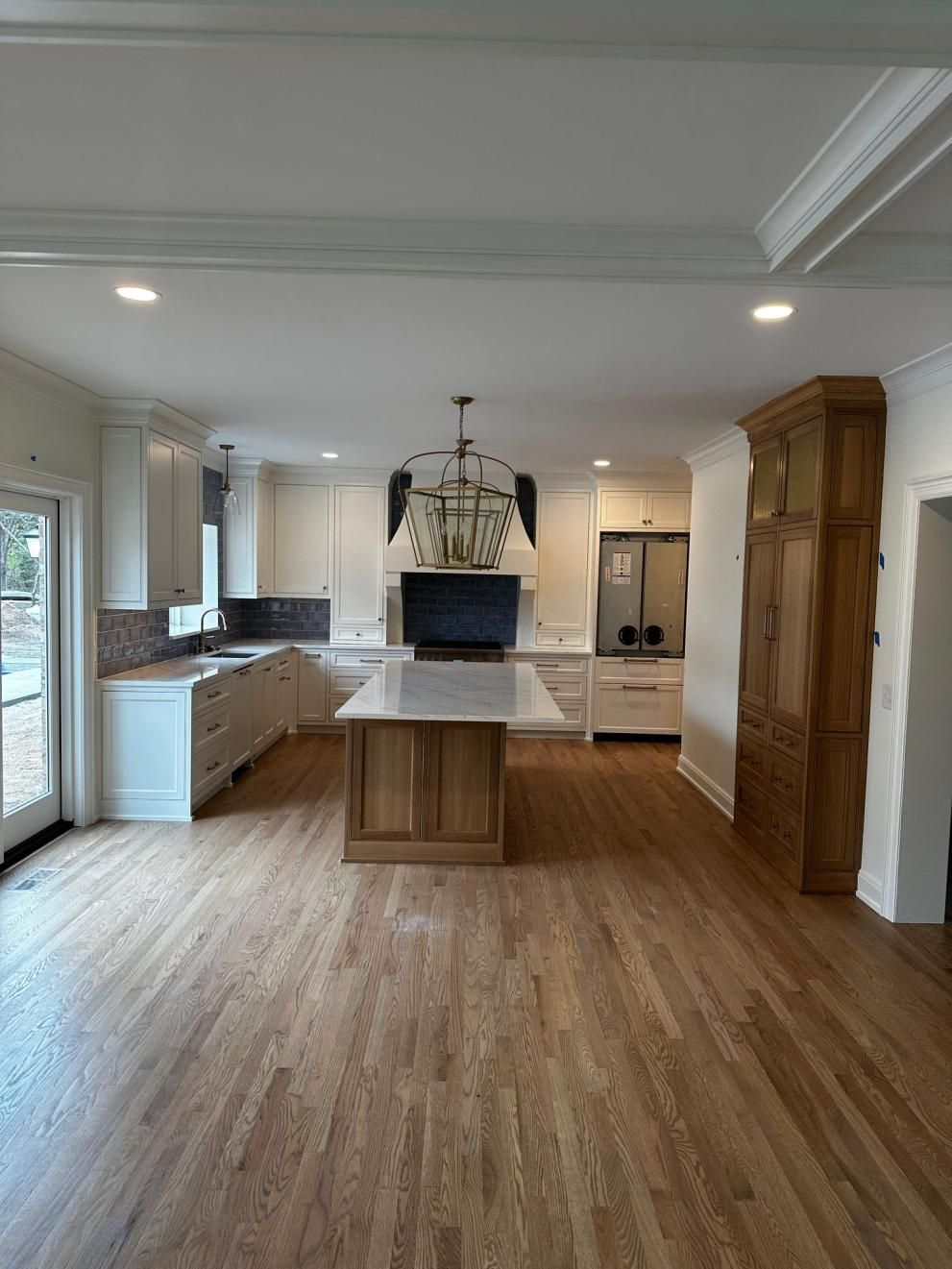 Bright kitchen with large island, white cabinets, wood floors, and stainless steel appliances